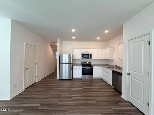 a large kitchen with stainless steel appliances kitchen island a large counter top and wooden floors