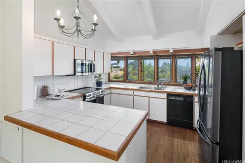 a kitchen with a refrigerator a sink dishwasher a stove and a dining table with wooden floor