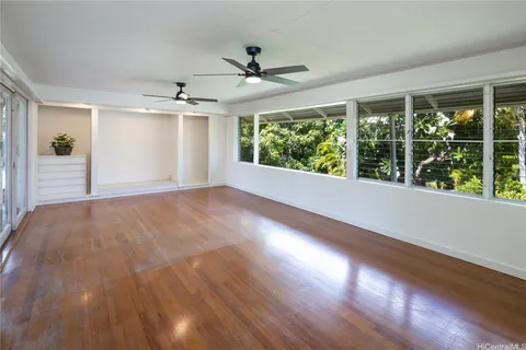 a view of a livingroom with wooden floor a ceiling fan and windows