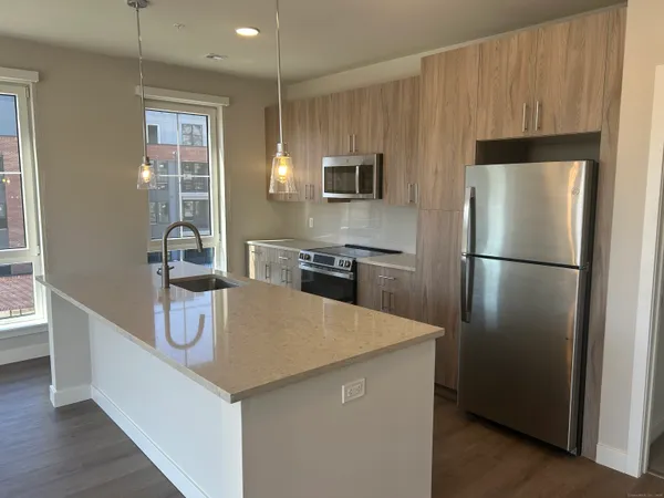 a kitchen with stainless steel appliances granite countertop a refrigerator a stove and a sink with wooden floor