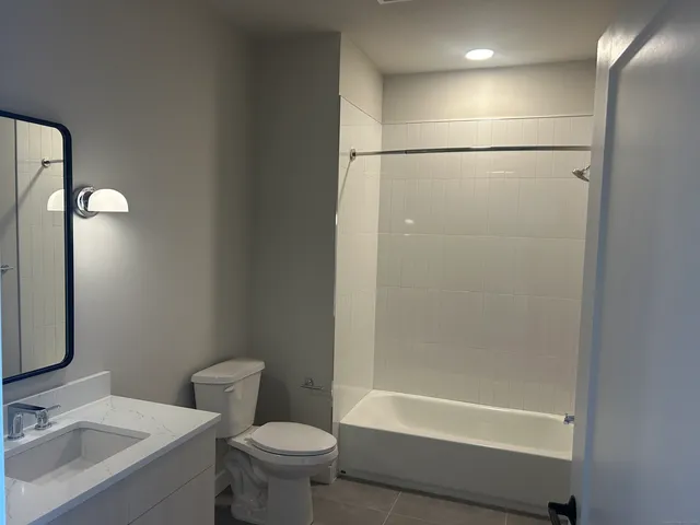 a bathroom with a bathtub shower sink vanity and toilet
