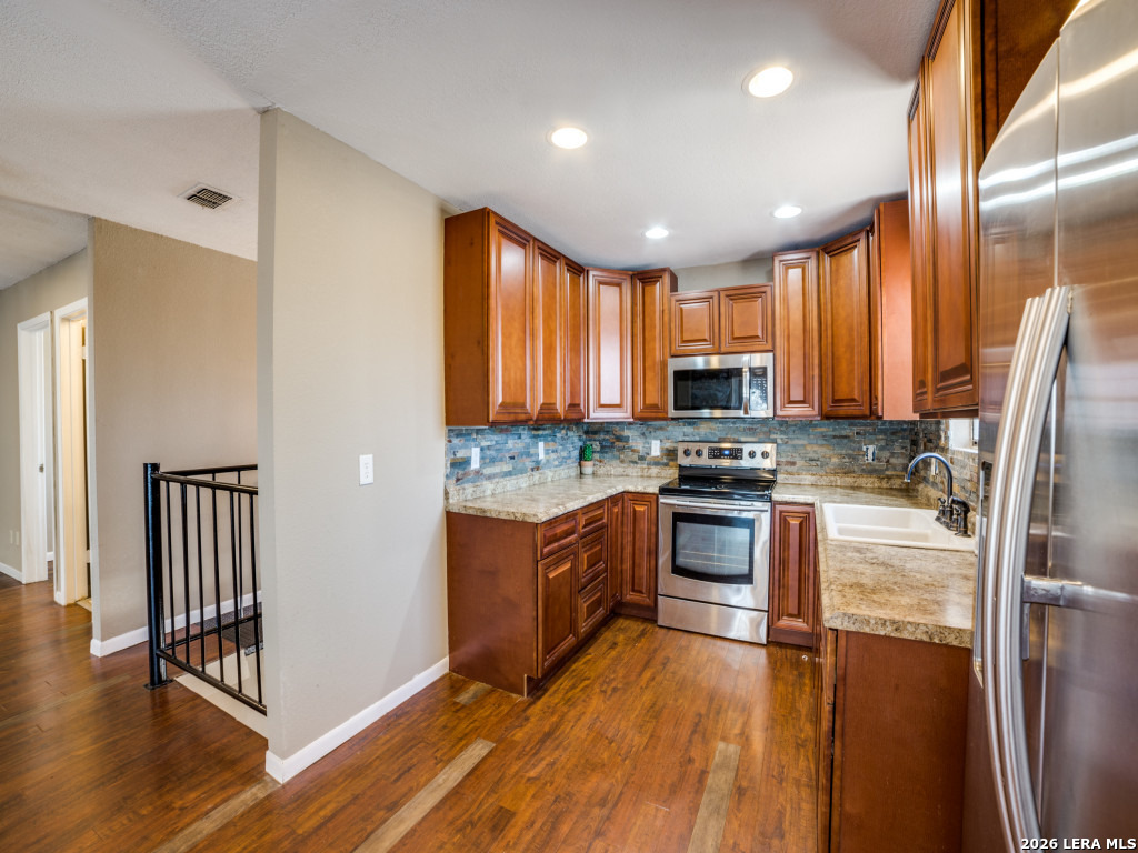 6953 Von Ormy Road Von Ormy, TX 78073 - Photo 9 of 28 a kitchen with stainless steel appliances granite countertop a stove a sink and a refrigerator