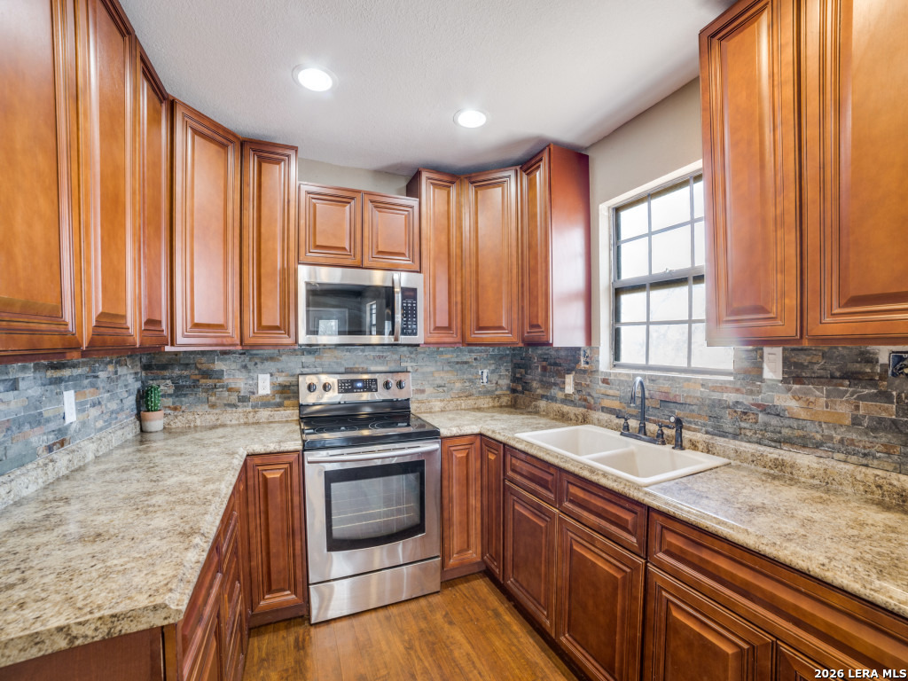 6953 Von Ormy Road Von Ormy, TX 78073 - Photo 10 of 28 a kitchen with stainless steel appliances granite countertop a sink a stove and a microwave