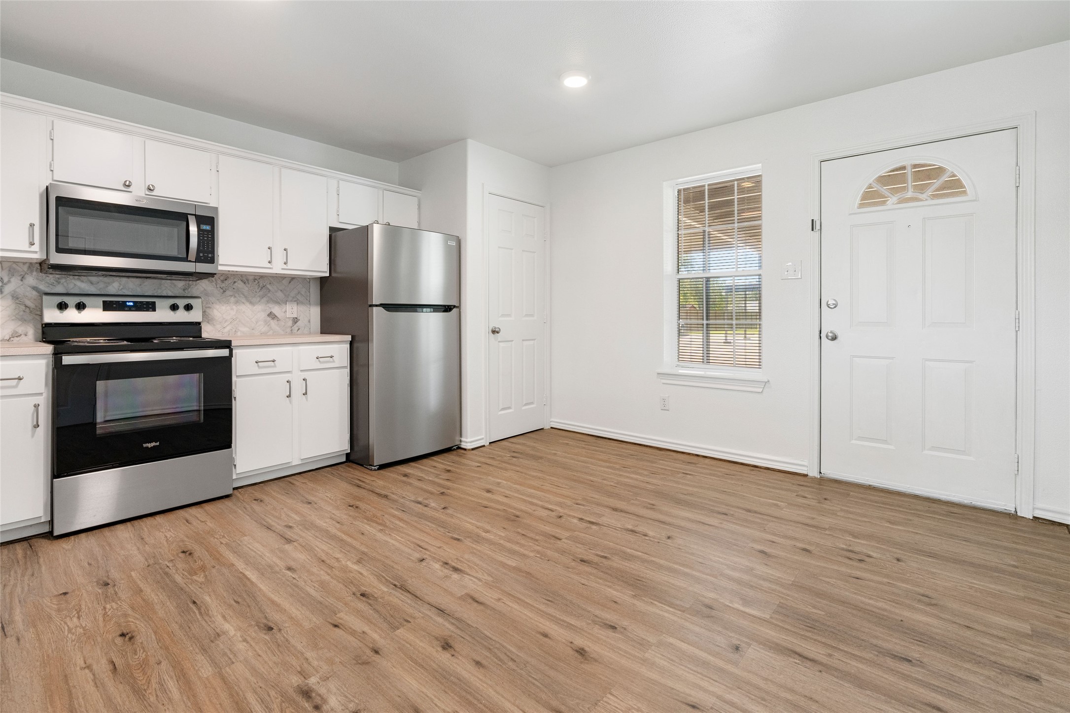 210 Brazos Street, Unit 102 Brazoria, TX 77422 - Photo 5 of 20 a view of kitchen with stainless steel appliances granite countertop a stove top oven a refrigerator with white cabinets and wooden floor