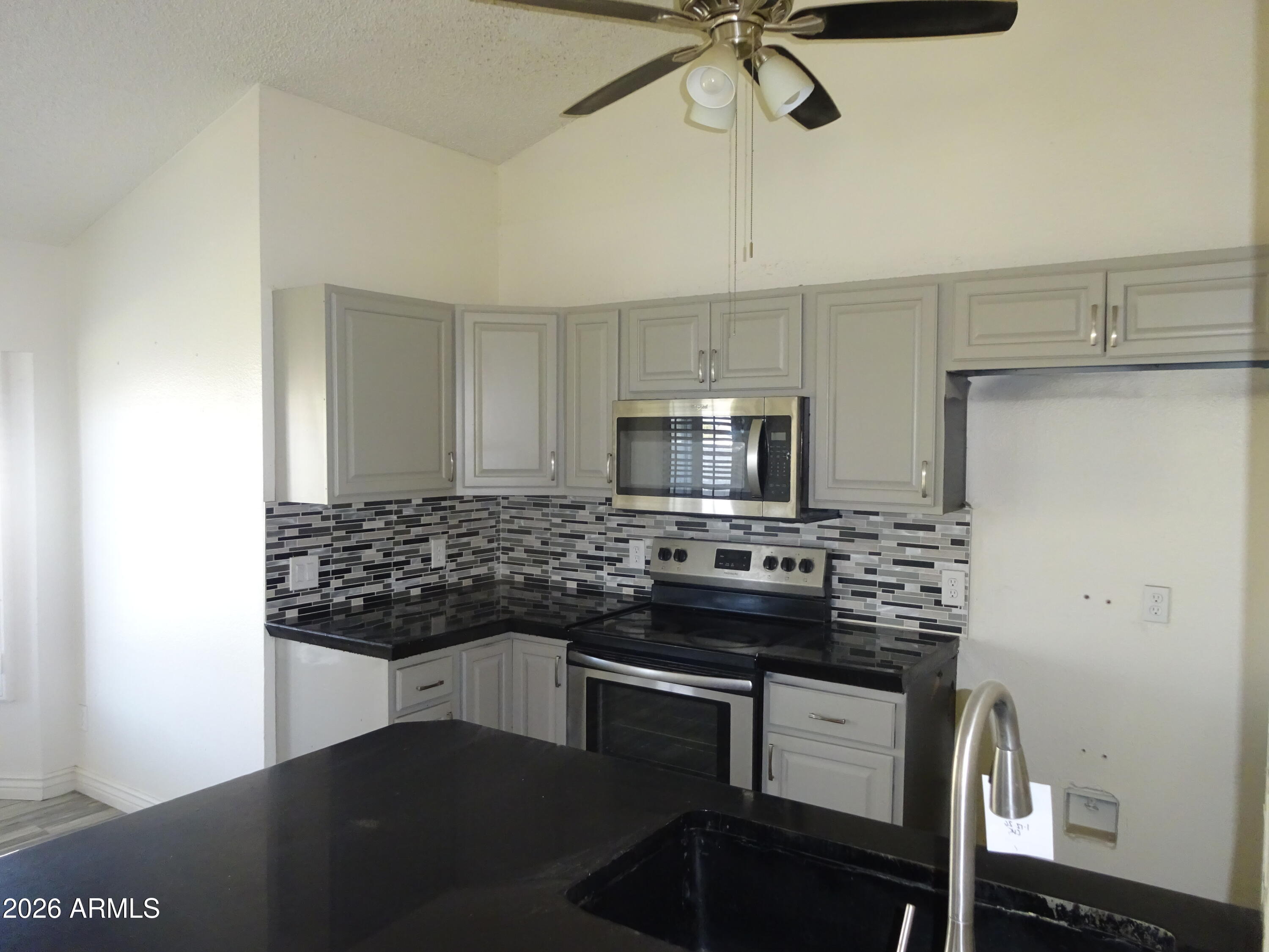 8602 West Wethersfield Road Peoria, AZ 85381 - Photo 11 of 26 a kitchen with stainless steel appliances kitchen island granite countertop a stove and a sink