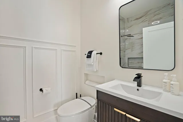 a bathroom with a toilet a sink a mirror and vanity