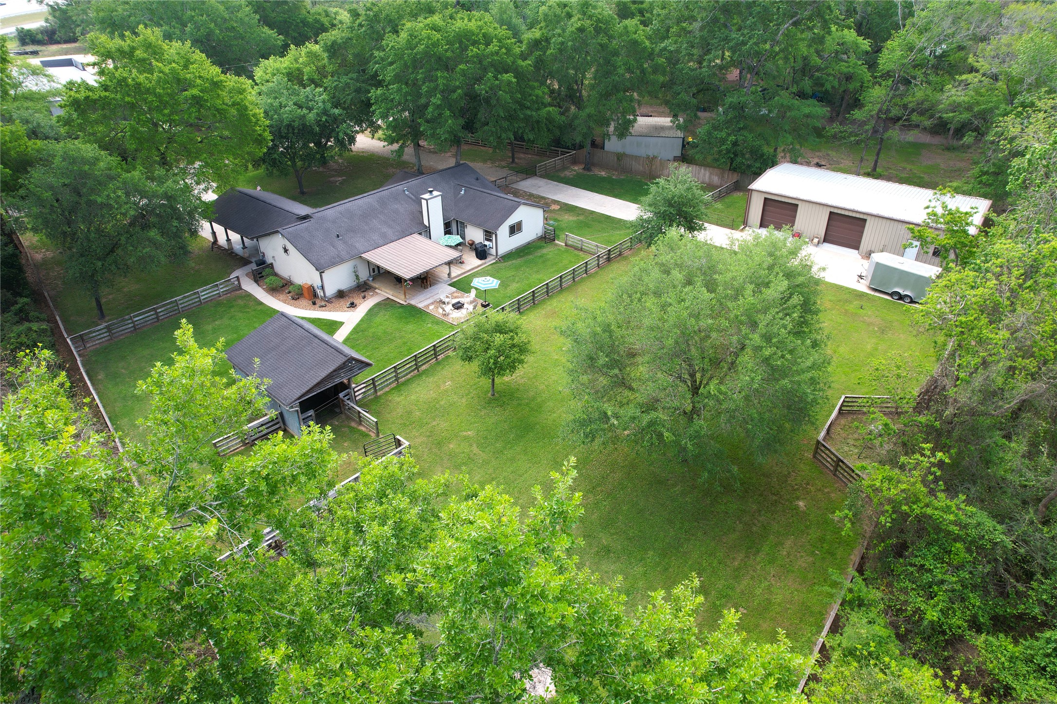 an aerial view of residential house with outdoor space and trees all around