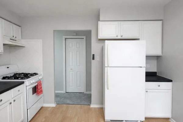a view of kitchen with refrigerator stove and white cabinets