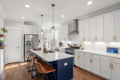 a kitchen with a sink dishwasher a stove a refrigerator and island with wooden floor