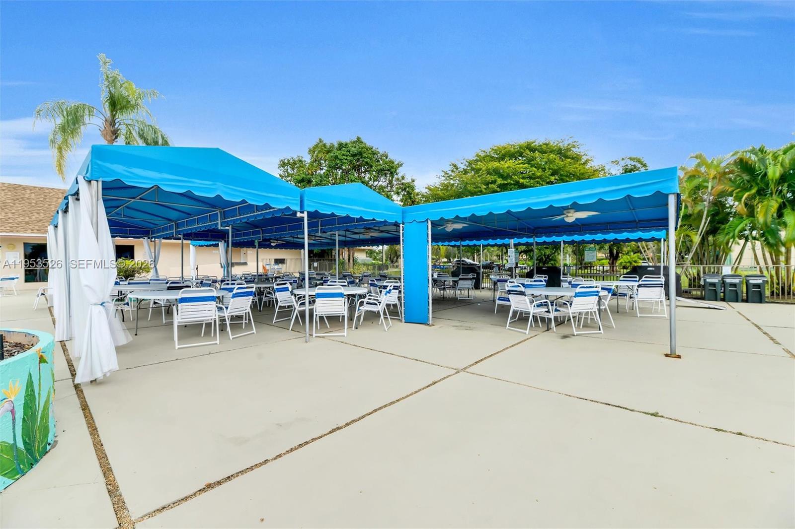 2601 North Nob Hill Road, Unit 407 Sunrise, FL 33322 - Photo 35 of 38 a view of a patio with table and chairs under an umbrella with a barbeque