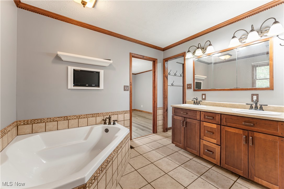 155 Ridgewood Boulevard Belpre, OH 45714 - Photo 43 of 49 Bathroom with ornamental molding, a garden tub, double vanity, light tile patterned flooring, and a textured ceiling