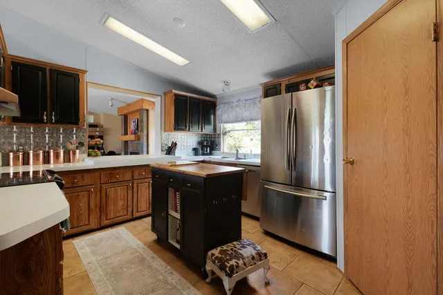 a kitchen with stainless steel appliances granite countertop a refrigerator a sink a stove a microwave and island