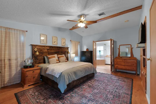 a bedroom with a bed wooden floor and a chandelier