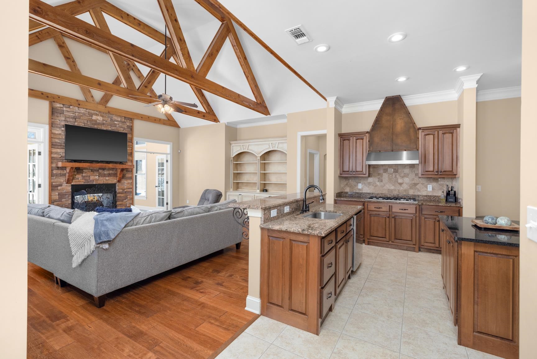 104 Eagle Trace Road Covington, TN 38019 - Photo 39 of 40 Kitchen with wood finish cabinets, a kitchen island with sink, dark stone counters, a stone fireplace, and open floor plan