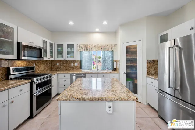 a kitchen with stainless steel appliances granite countertop a refrigerator a stove and a sink