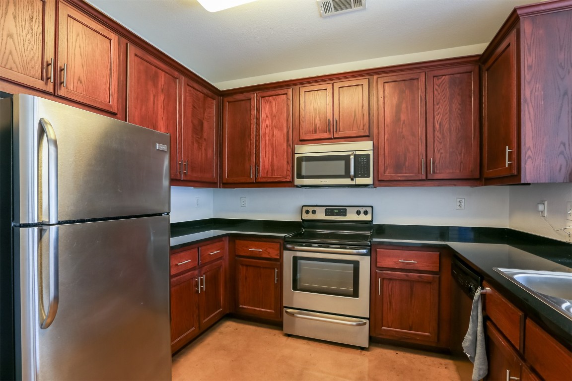 910 West 25th Street, Unit 509 Austin, TX 78705 - Photo 11 of 31 a kitchen with stainless steel appliances granite countertop a refrigerator stove a sink and dishwasher with wooden cabinets