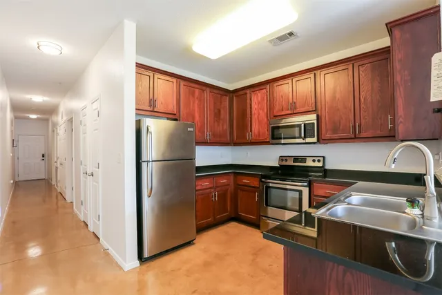 a kitchen with stainless steel appliances granite countertop a refrigerator stove top oven and sink