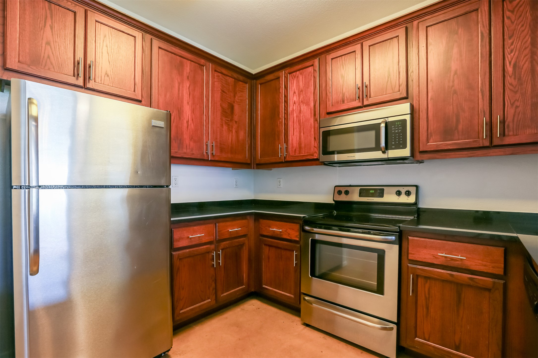 910 West 25th Street, Unit 509 Austin, TX 78705 - Photo 6 of 31 a kitchen with granite countertop wooden cabinets stainless steel appliances and a refrigerator
