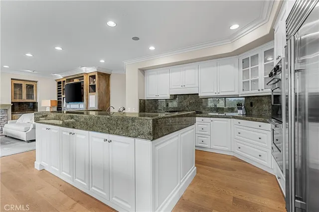 a kitchen with stainless steel appliances granite countertop a stove top oven a sink a refrigerator and white cabinets