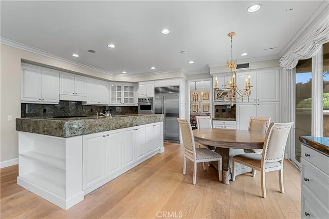 a kitchen with stainless steel appliances a dining table chairs and wooden floor