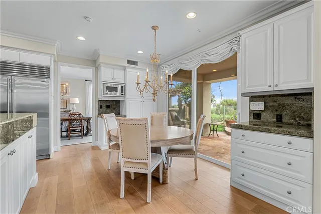 a kitchen with stainless steel appliances granite countertop a table chairs refrigerator and sink