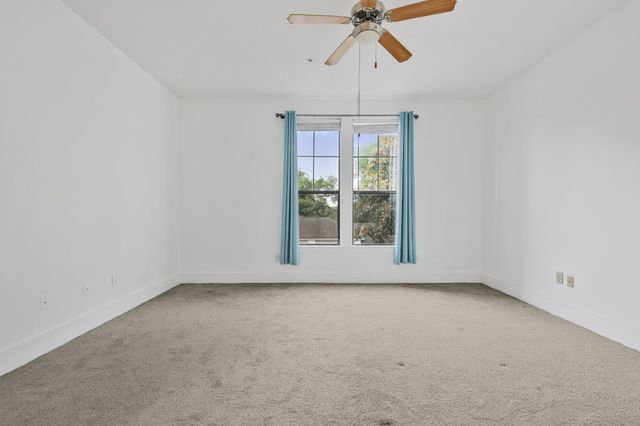 an empty room with ceiling fan and window