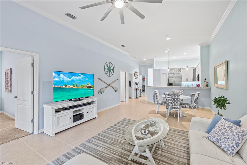 1285 Sweetwater Cove, Unit 2106 Naples, FL 34110 - Photo 12 of 38 a living room with furniture a flat screen tv and a dining table