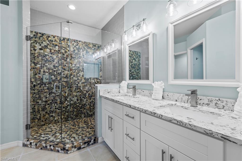 1285 Sweetwater Cove, Unit 2106 Naples, FL 34110 - Photo 14 of 38 a bathroom with a granite countertop sink a mirror a and a shower