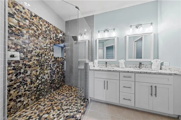 a bathroom with a granite countertop sink a mirror a and a shower