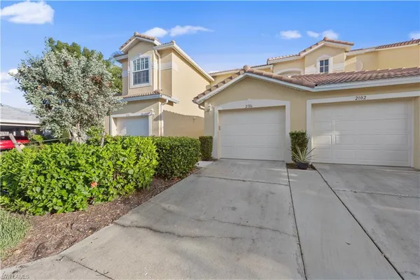 a view of white house with a yard and potted plants