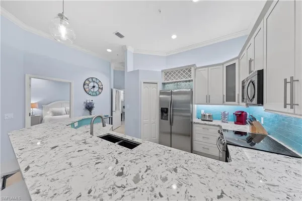 a kitchen with stainless steel appliances kitchen island granite countertop a refrigerator and a sink