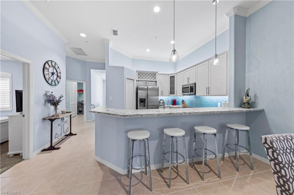 1285 Sweetwater Cove, Unit 2106 Naples, FL 34110 - Photo 6 of 38 a kitchen with cabinets and chairs