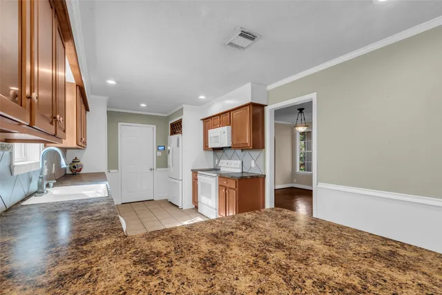 a open kitchen with granite countertop a refrigerator stove oven dining table and chairs