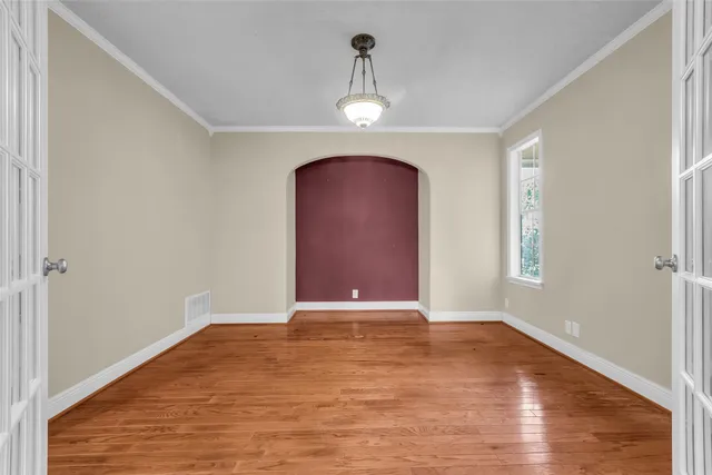 a view of an empty room with wooden floor and windows