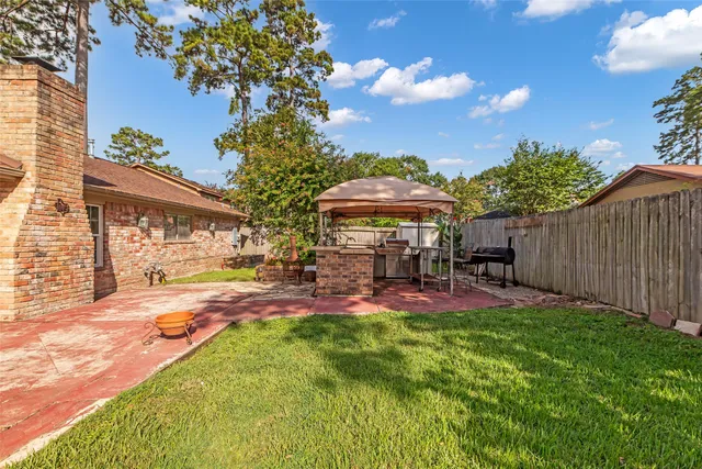 a view of a backyard with table and chairs under an umbrella with a fire pit
