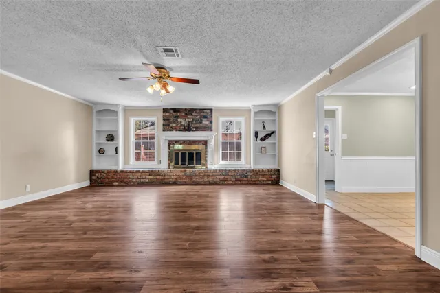 an empty room with wooden floor fireplace and a window