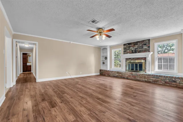 a view of an empty room with window and wooden floor