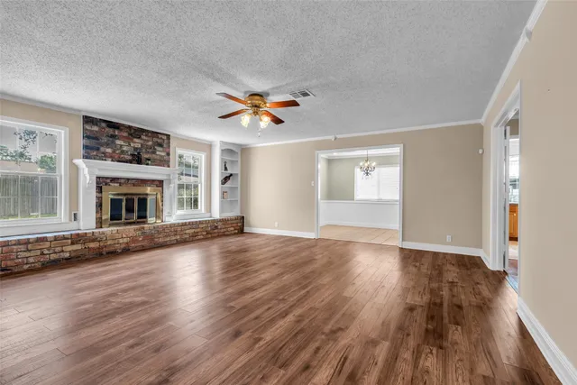 an empty room with wooden floor fireplace and windows