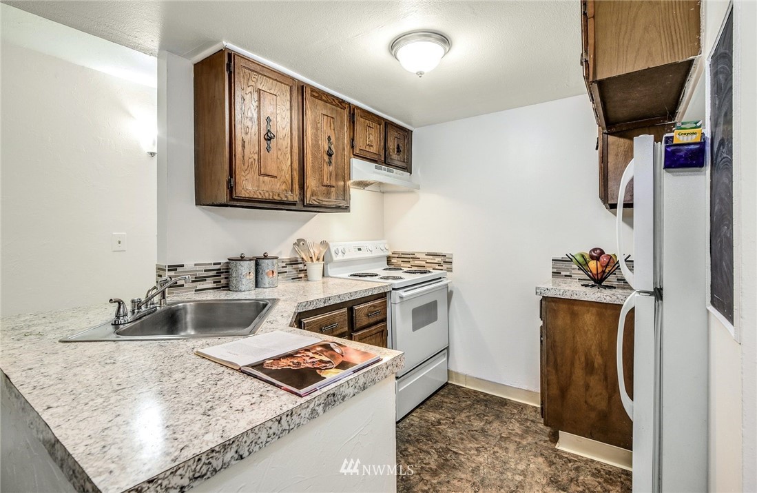 7511 14th Avenue Southwest Seattle, WA 98106 - Photo 4 of 16 a kitchen with stainless steel appliances granite countertop a sink stove and refrigerator