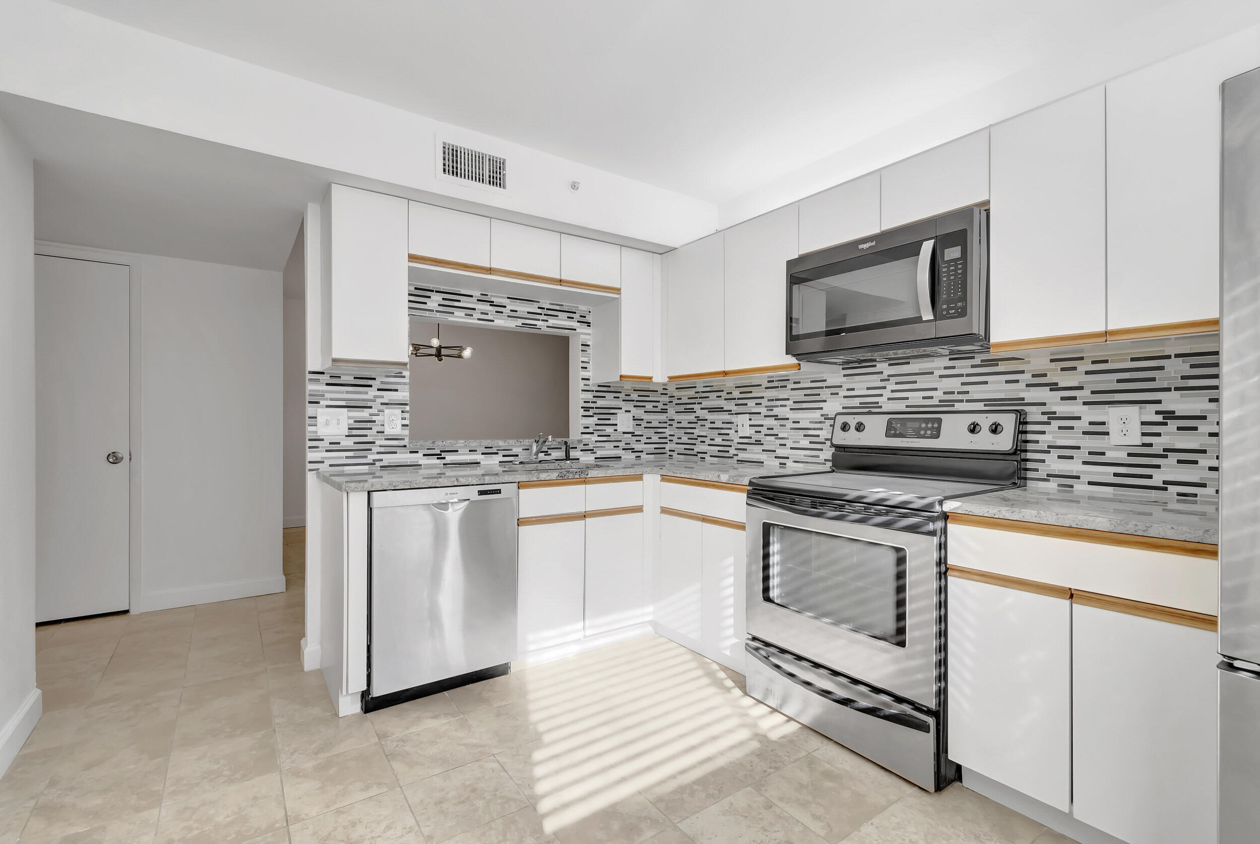 15364 Lakes Of Delray Boulevard, Unit 45 Delray Beach, FL 33484 - Photo 26 of 56 a kitchen with granite countertop white cabinets sink and stainless steel appliances