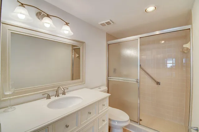 a bathroom with a granite countertop shower sink vanity mirror and toilet