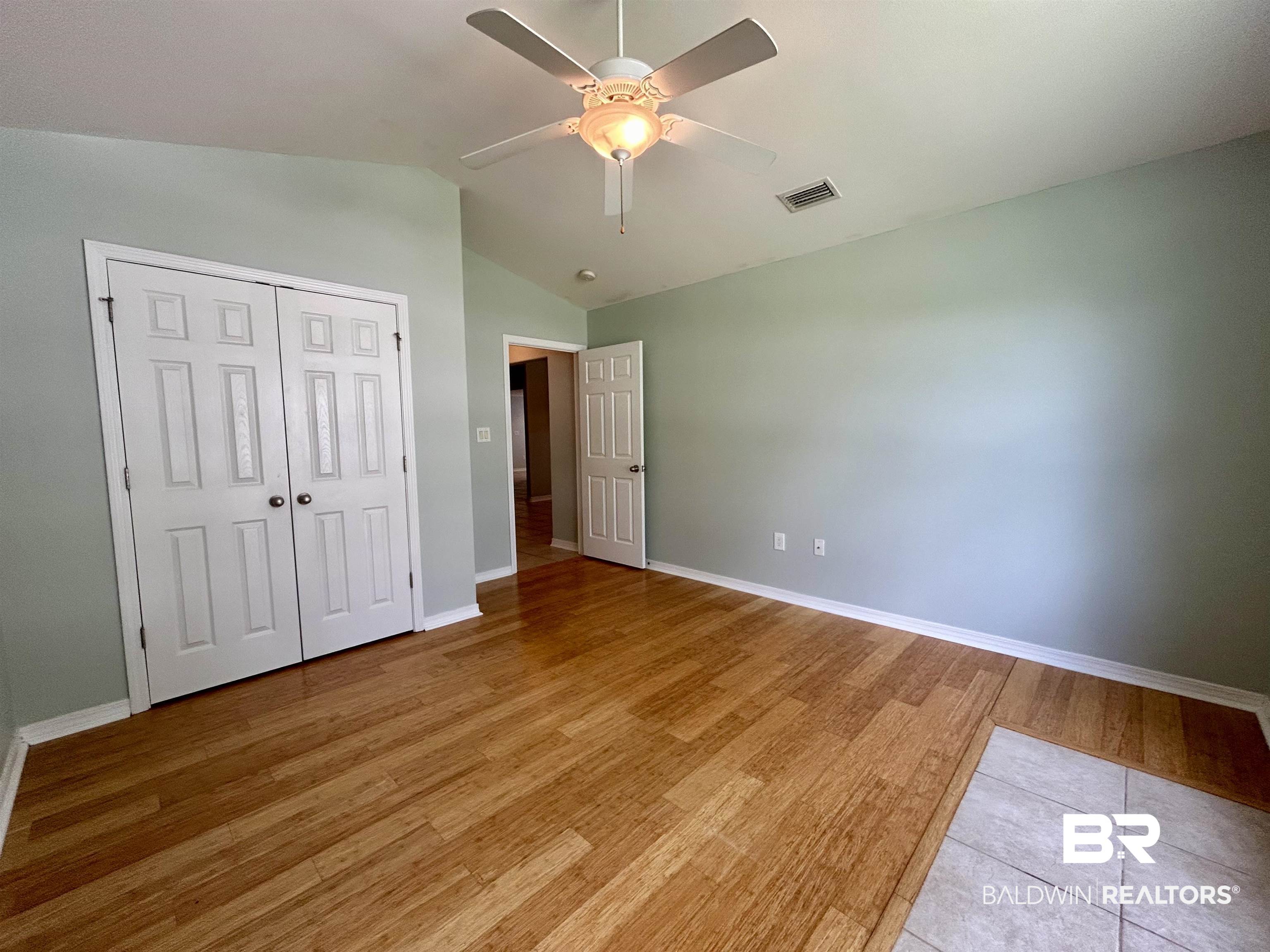7198 Raintree Lane Gulf Shores, AL 36542 - Photo 21 of 33 Vaulted ceiling room featuring wood-finish flooring, light green wall paint, and white trim