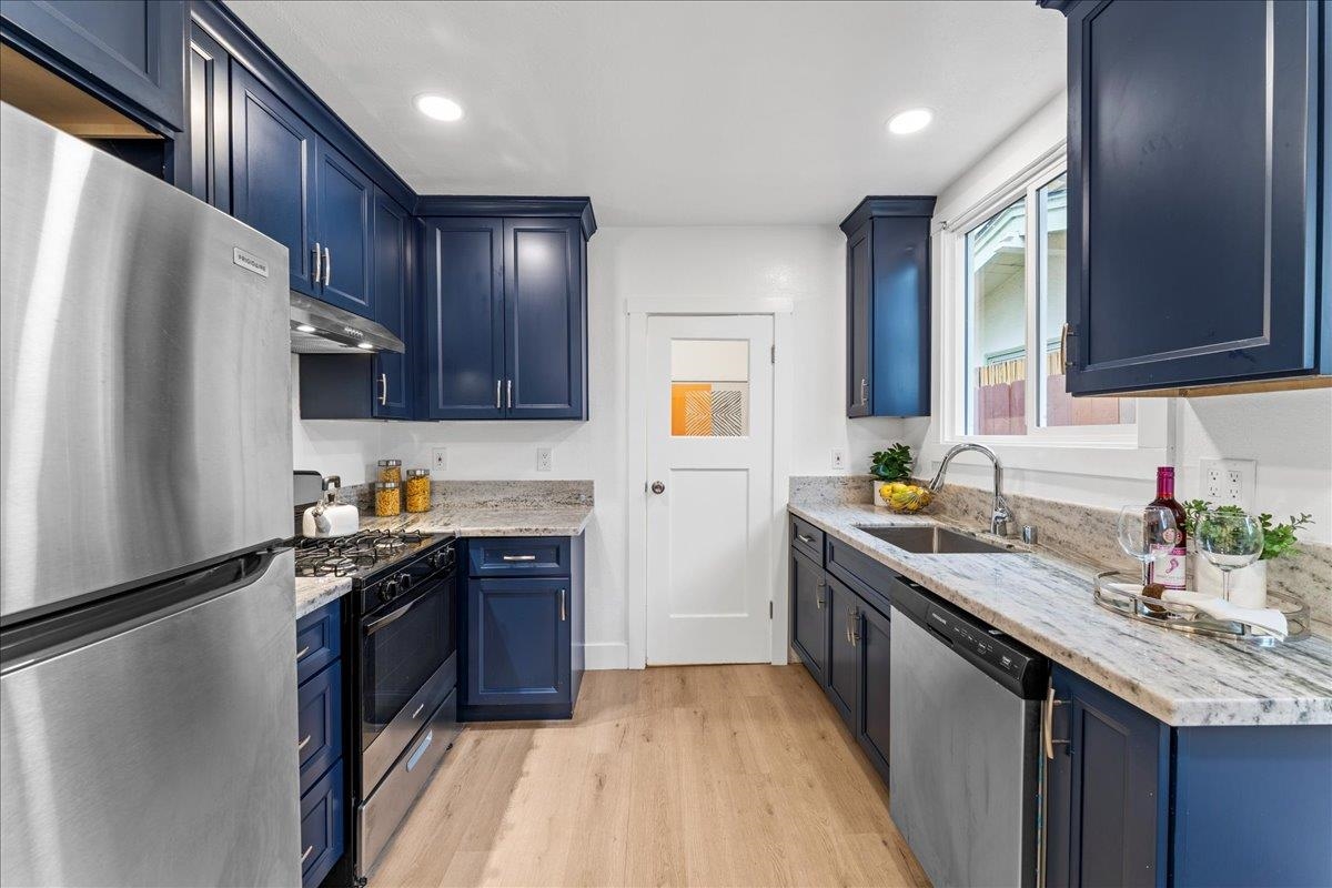 2717 Mabel Street Berkeley, CA 94702 - Photo 16 of 59 Kitchen with blue cabinetry, stainless steel appliances, light wood-style flooring, light stone counters, and recessed lighting