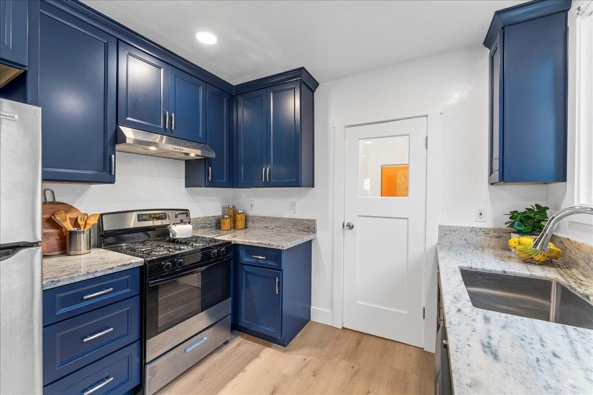 2717 Mabel Street Berkeley, CA 94702 - Photo 20 of 59 Kitchen featuring blue cabinets, stainless steel appliances, light stone counters, light wood-style flooring, and recessed lighting