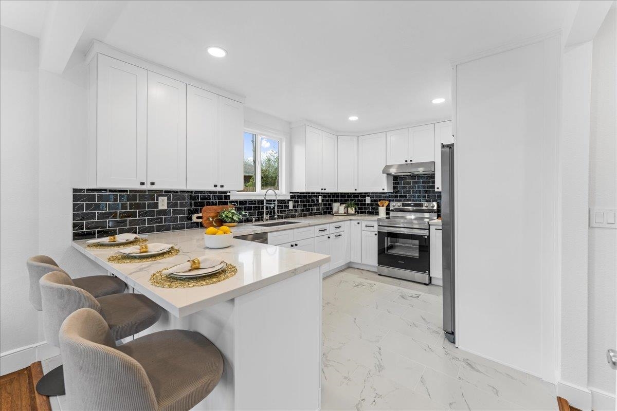 2717 Mabel Street Berkeley, CA 94702 - Photo 29 of 59 Kitchen featuring white cabinetry, a peninsula, a kitchen breakfast bar, electric stove, and light stone countertops