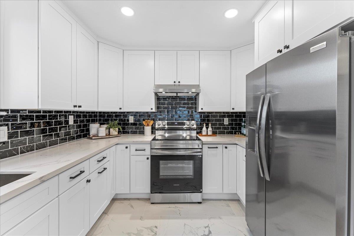 2717 Mabel Street Berkeley, CA 94702 - Photo 32 of 59 Kitchen with stainless steel appliances, light stone countertops, white cabinets, backsplash, and light marble finish flooring