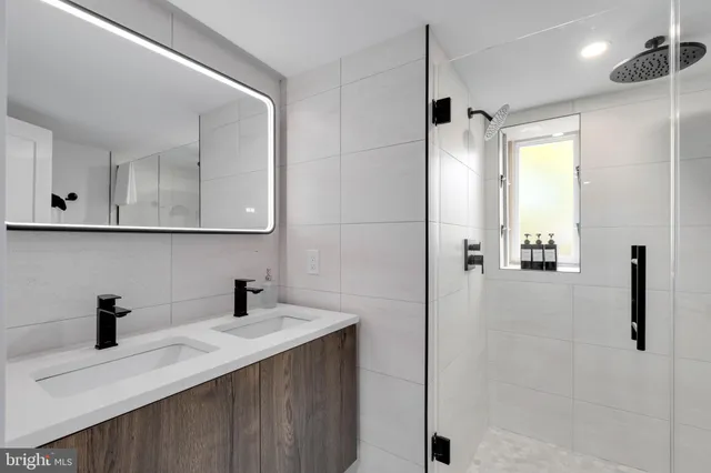 a bathroom with a double vanity sink a mirror and shower
