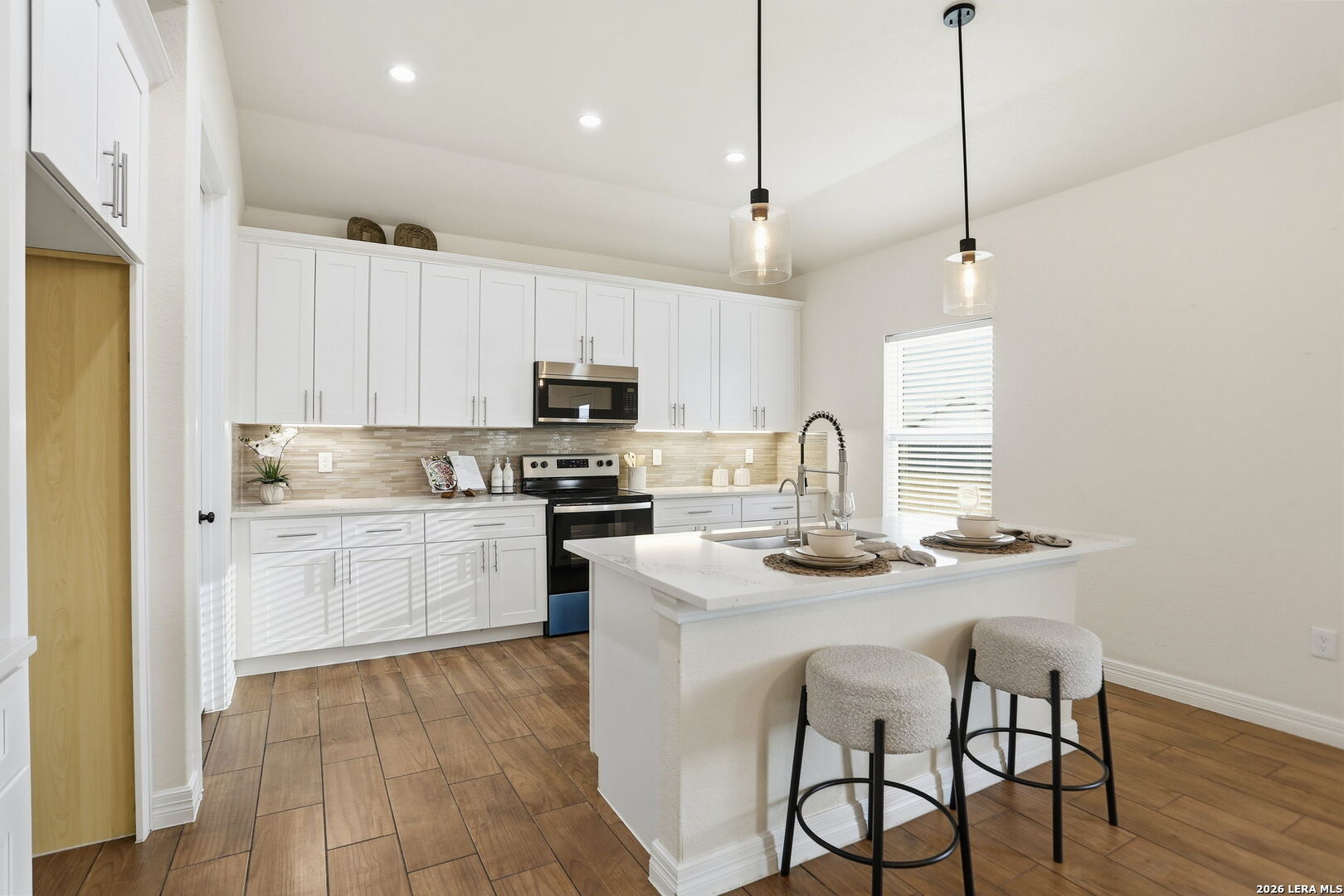 100 West Short Meadow Drive Lytle, TX 78052 - Photo 17 of 51 a kitchen with kitchen island granite countertop a sink stove and white cabinets with wooden floor