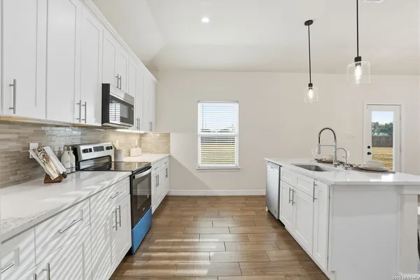 a kitchen with kitchen island granite countertop a sink a counter space appliances and cabinets