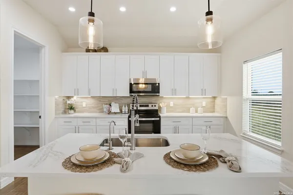 a kitchen with granite countertop white cabinets and stainless steel appliances